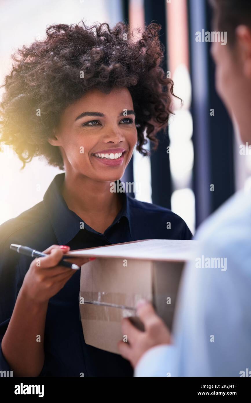 Shes impressionato dal suo rapido turnaround. Shot di una donna d'affari felice firma per un pacchetto consegnato da un corriere nel suo ufficio. Foto Stock