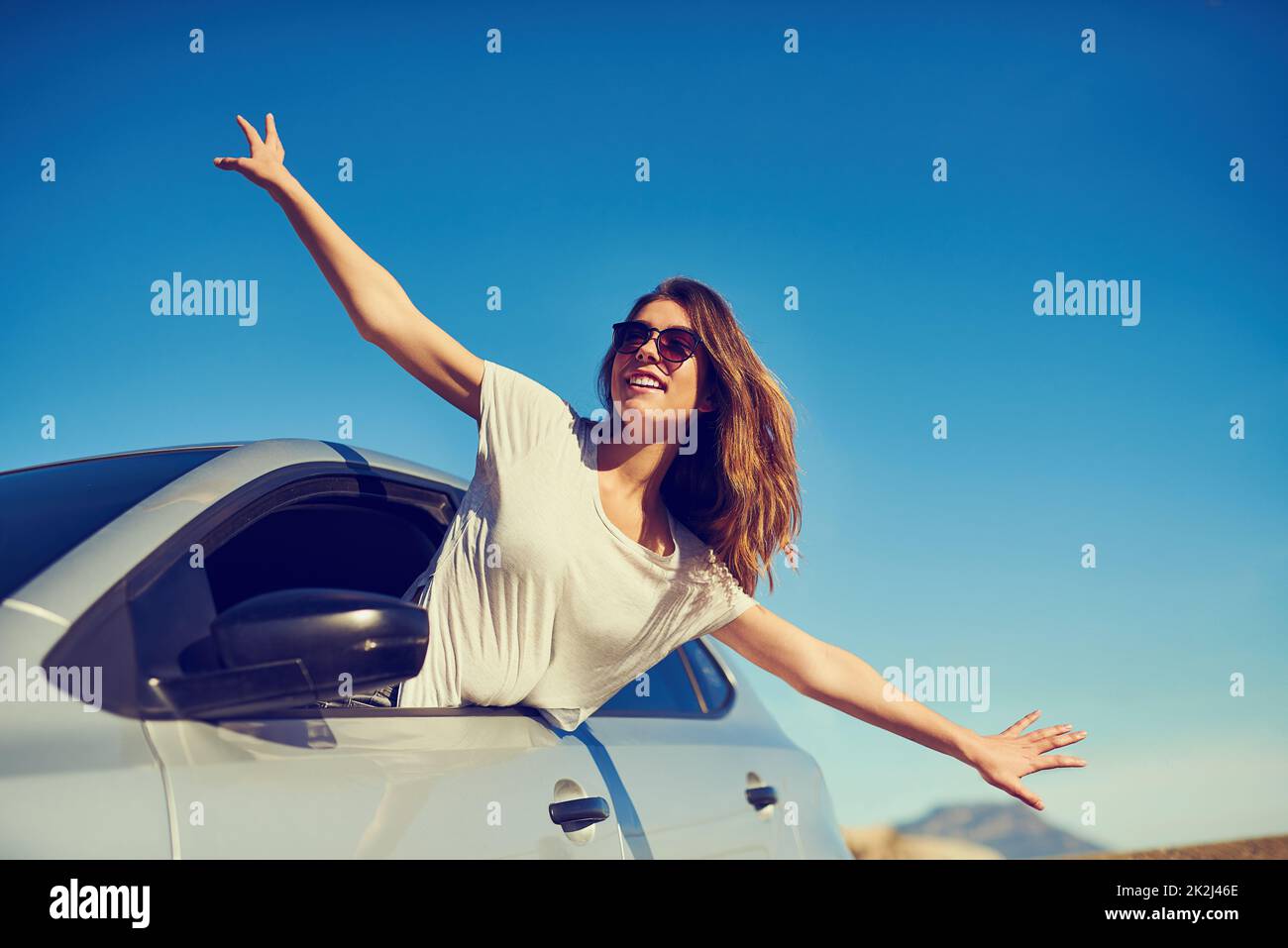 Libertà totale. Scatto di una giovane donna che si stende fuori dal finestrino della sua auto con le braccia tese. Foto Stock