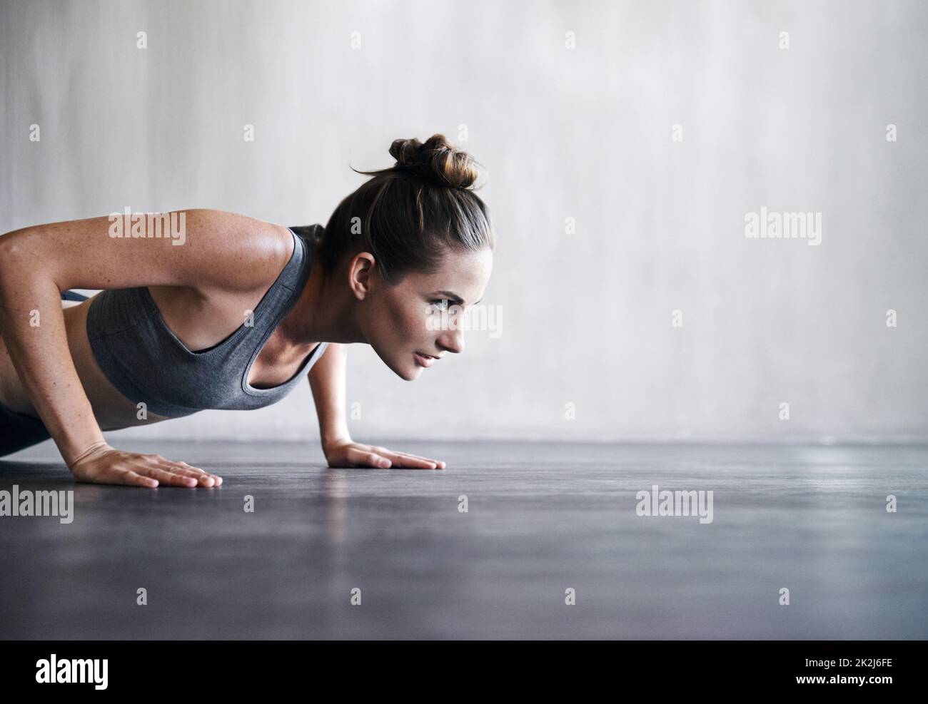 Superare i limiti. Shot di una donna che fa push-up in palestra. Foto Stock