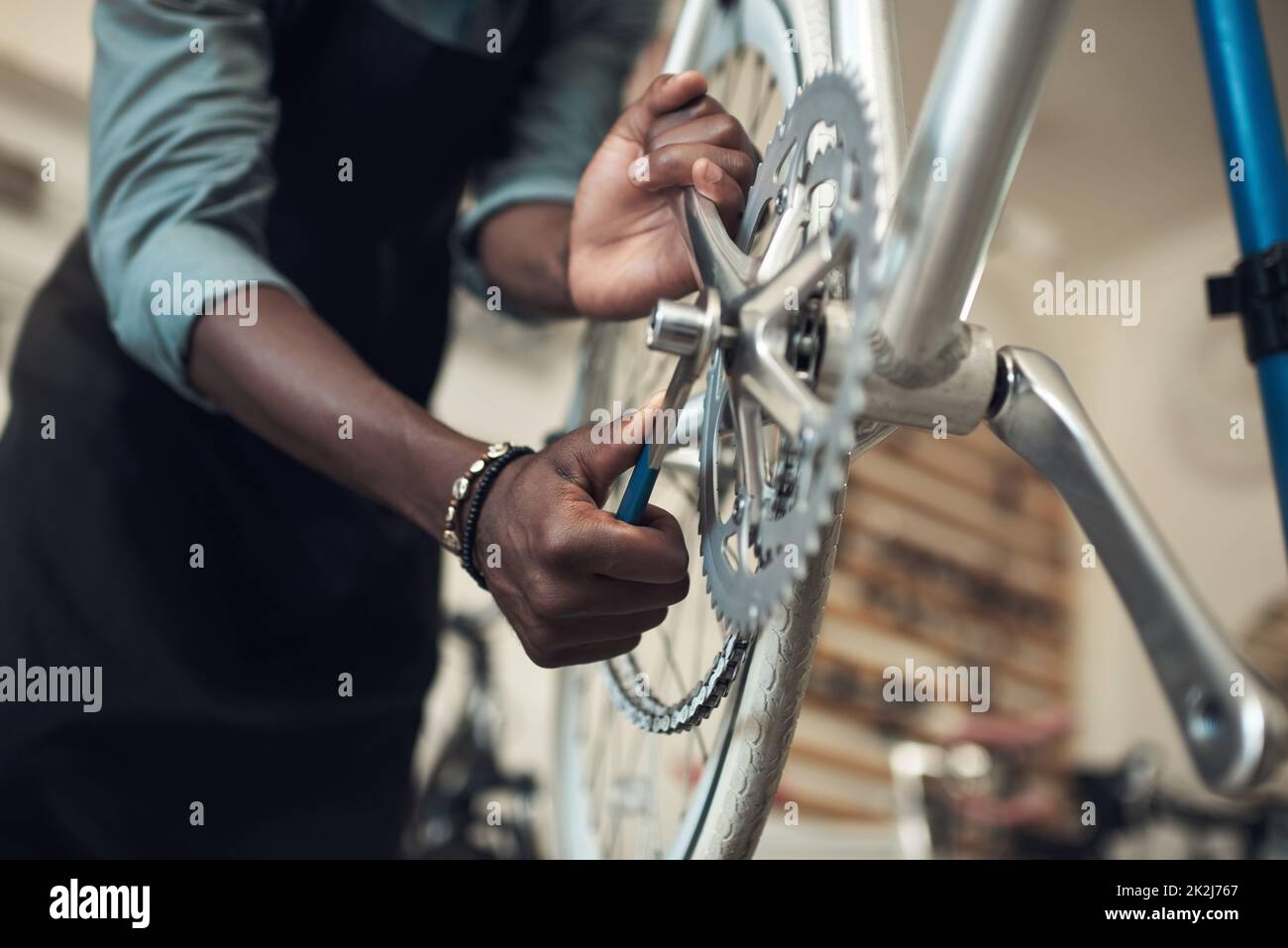 Non vogliamo che questo cada. Girato di un uomo irriconoscibile in piedi da solo nel suo negozio e riparare una ruota di bicicletta. Foto Stock