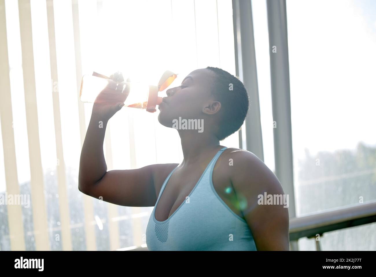 Per cambiare il tuo corpo, cambia la tua mente. Shot di una giovane donna che beve acqua dopo il suo allenamento su uno sfondo urbano. Foto Stock