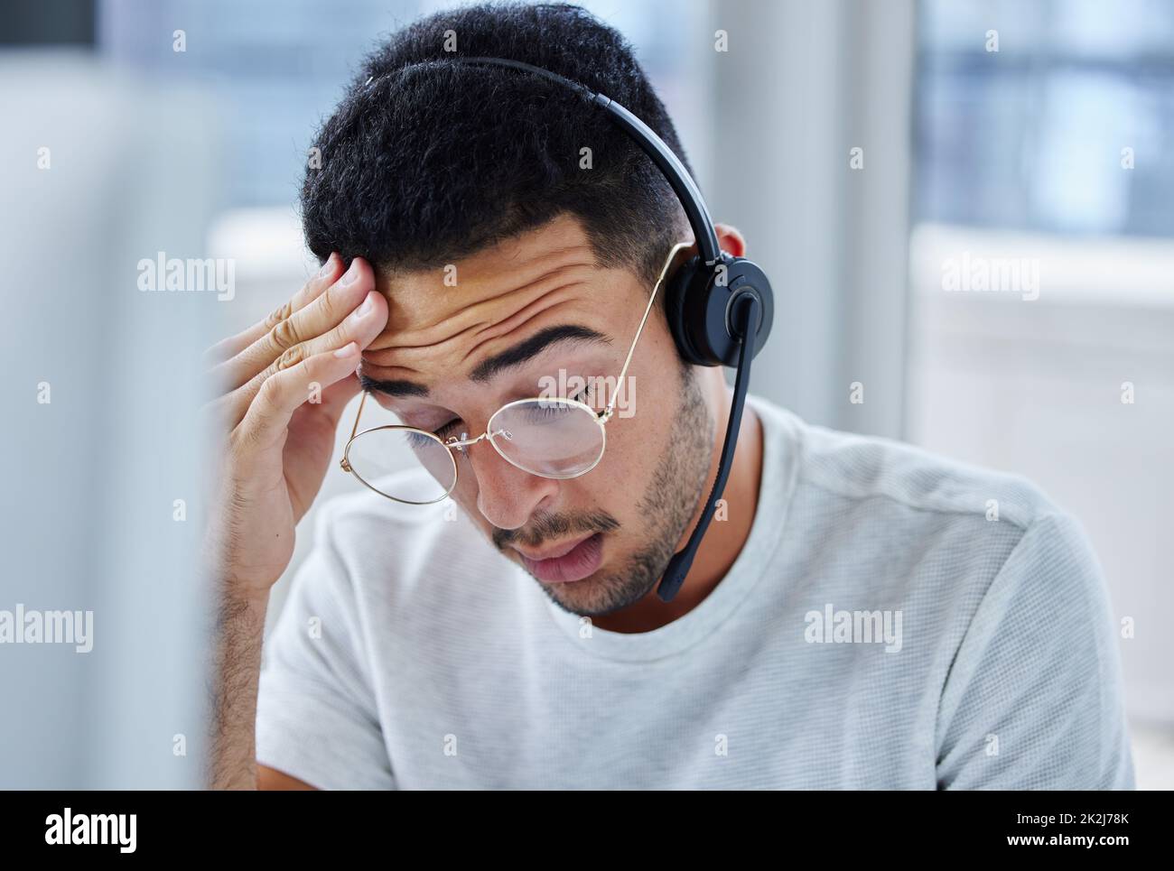 Spero di poter raggiungere oggi la mia scadenza. Shot di un giovane uomo d'affari che soffre di mal di testa alla sua scrivania nel suo ufficio. Foto Stock