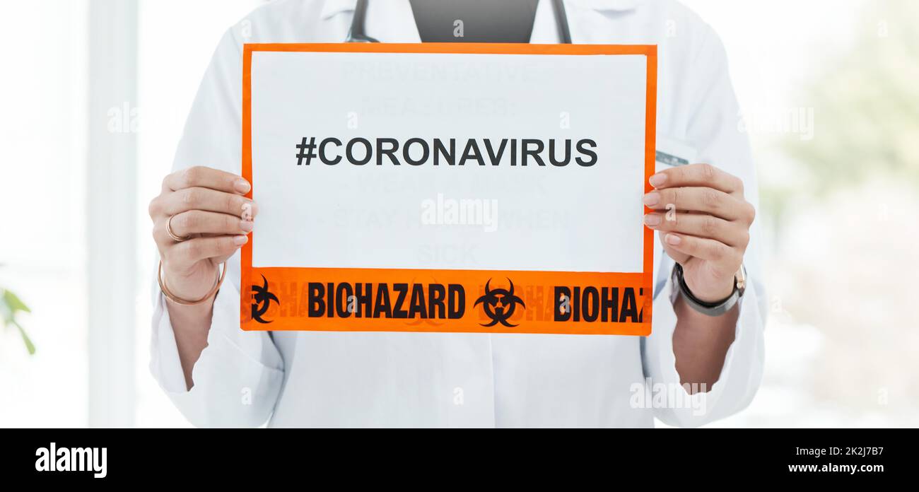 Sulla lotta contro il coronavirus. Shot di un medico che tiene un segno con CORONAVIRUS su di esso. Foto Stock