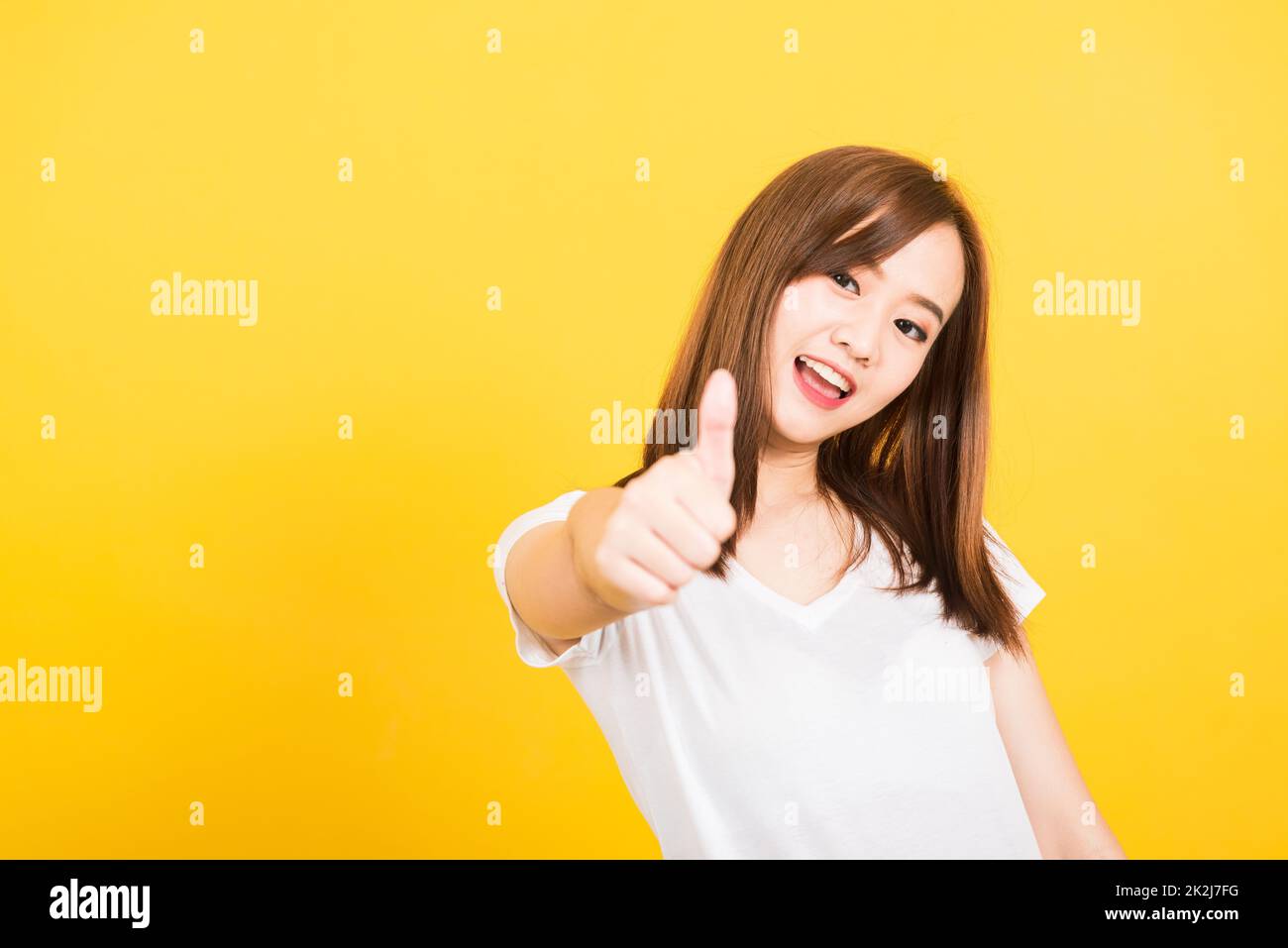 donna adolescente in piedi t-shirt mostrando gesturing dito pollice in su Foto Stock