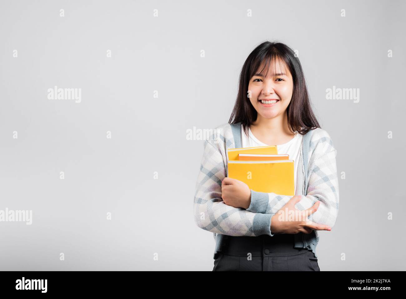 Donna giovane sorridente tenendo e abbracciare abbracciare il libro preferito per l'amante Foto Stock