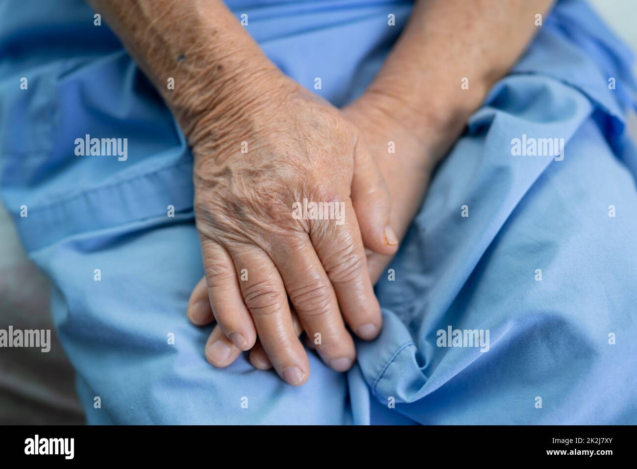 Donna anziana asiatica o anziana donna paziente tenere la sua mano con speranza mentre si siede a letto in ospedale infermieristico. Foto Stock