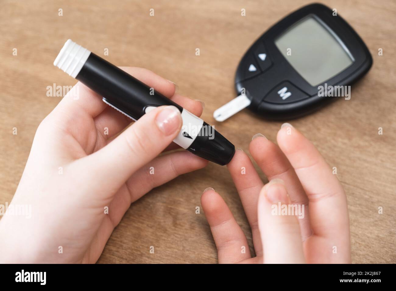 Le mani del bambino che usano Lancet sul dito per controllare il livello di zucchero nel sangue con il glucometro. Foto Stock