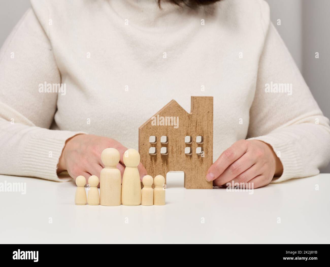 casa in legno e figure di una famiglia. Concetto di assicurazione immobiliare, famiglia felice Foto Stock