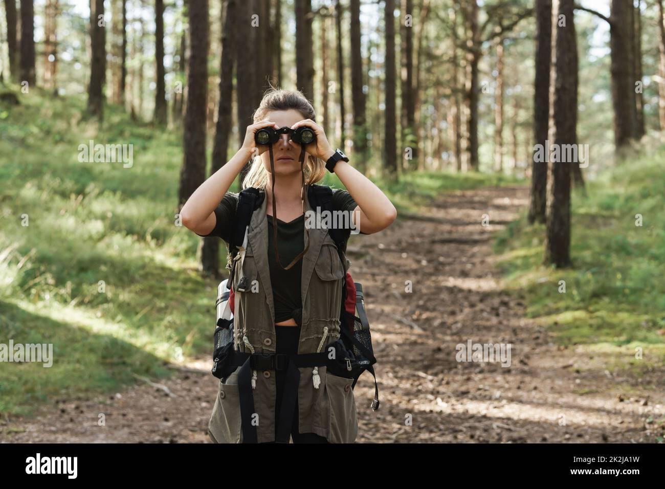 L'escursionista femminile utilizza il binocolo per il bird watching nella foresta verde Foto Stock