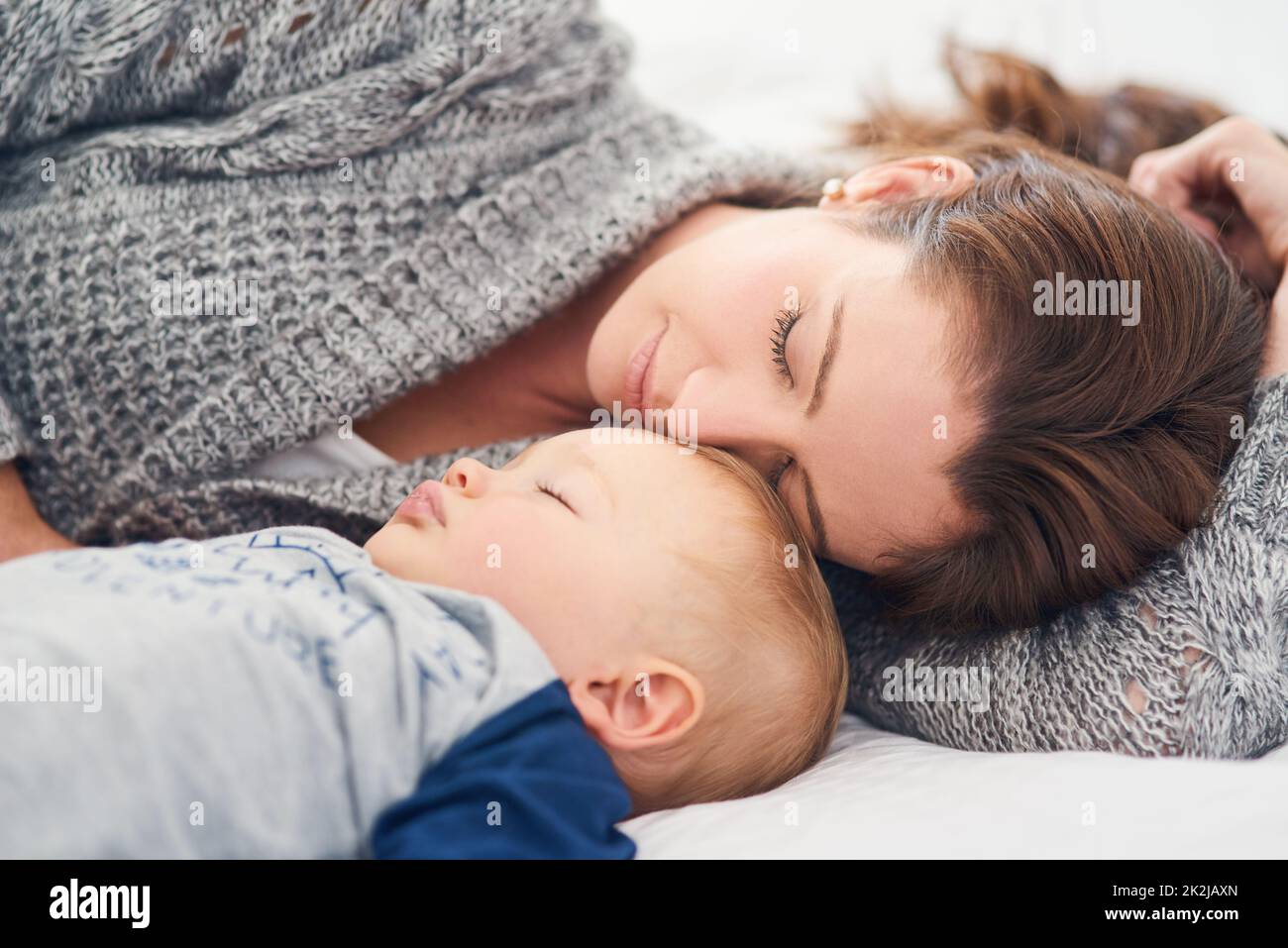 Esecuzione di uno snooze rapido. Scatto corto di una madre e del suo bambino che dormono insieme a casa. Foto Stock