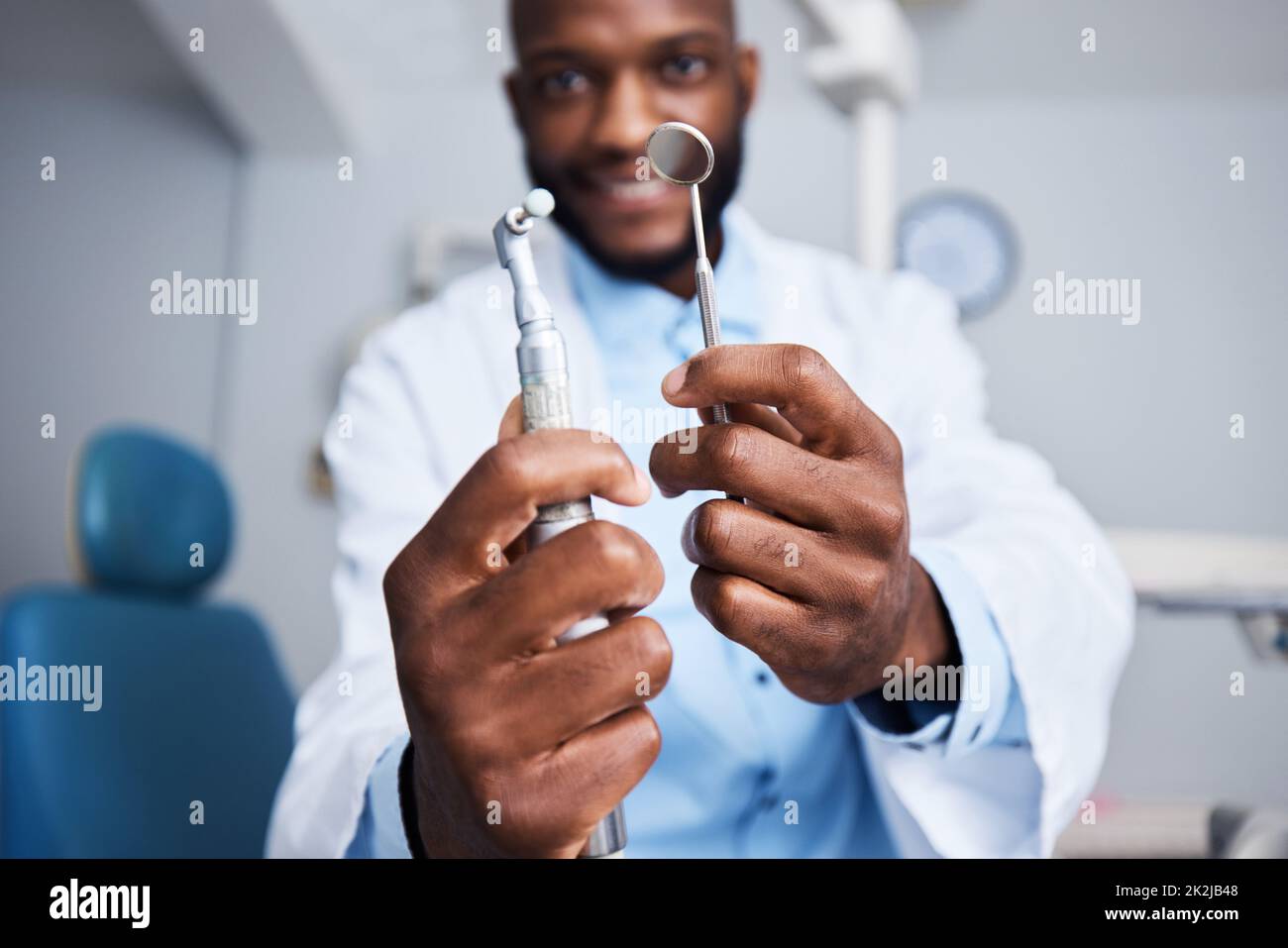 Un sorriso meravigliosamente luminoso che arriva fino in alto. Ritratto di un giovane uomo che tiene i denti strumenti di pulizia nel suo studio dentistico. Foto Stock