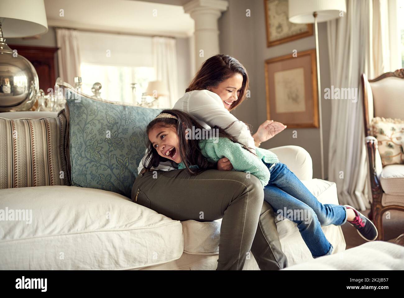 I momenti di mamma e figlia sono pieni di divertimento. Scatto di una madre e di una figlia che si divertono sul divano a casa. Foto Stock