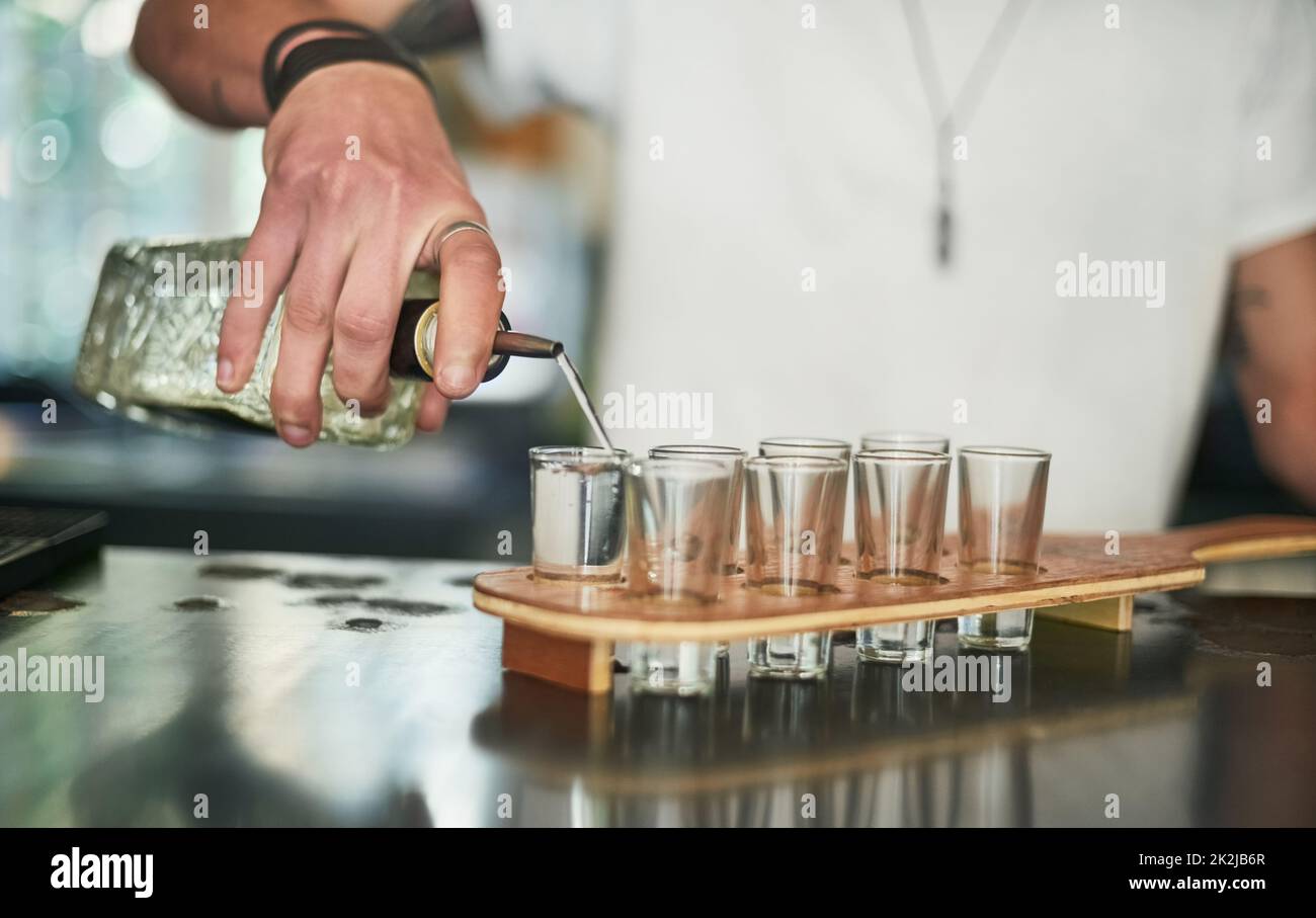 Inizia questa festa. Scatto ritagliato di un barista inidentificabile versando colpi dietro la barra. Foto Stock