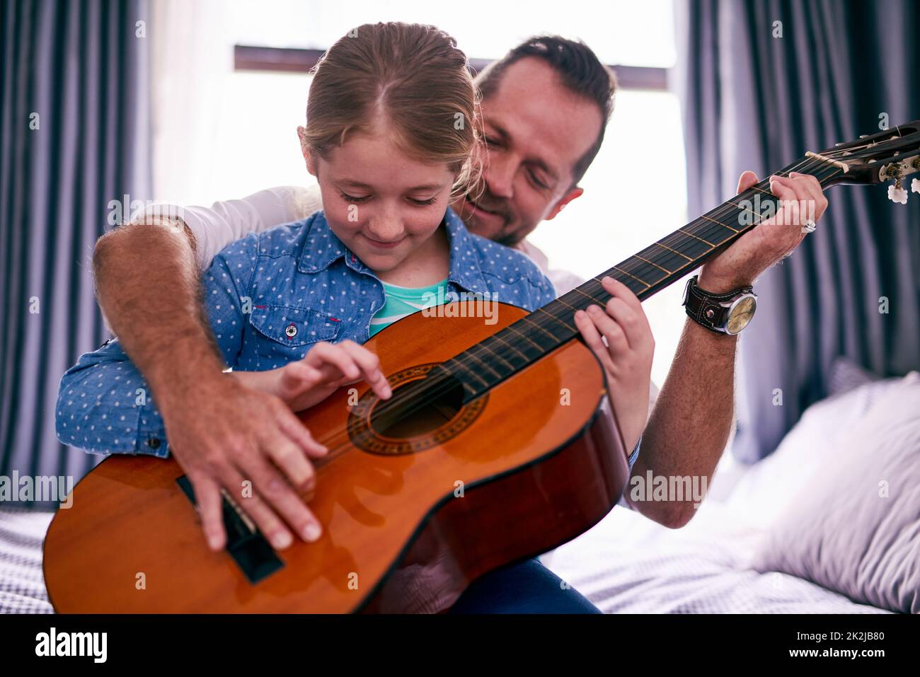 Legame musicale. Scatto corto di un padre e di una figlia che suonano la chitarra insieme a casa. Foto Stock