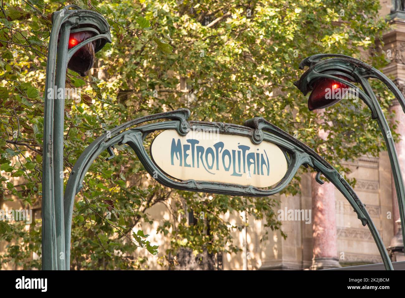 Parigi, Francia. Agosto 2022. Metro di stile retrò giallo segno della rete metropolitana di Parigi su uno sfondo verde alberi frondosi. Alta qualità pho Foto Stock