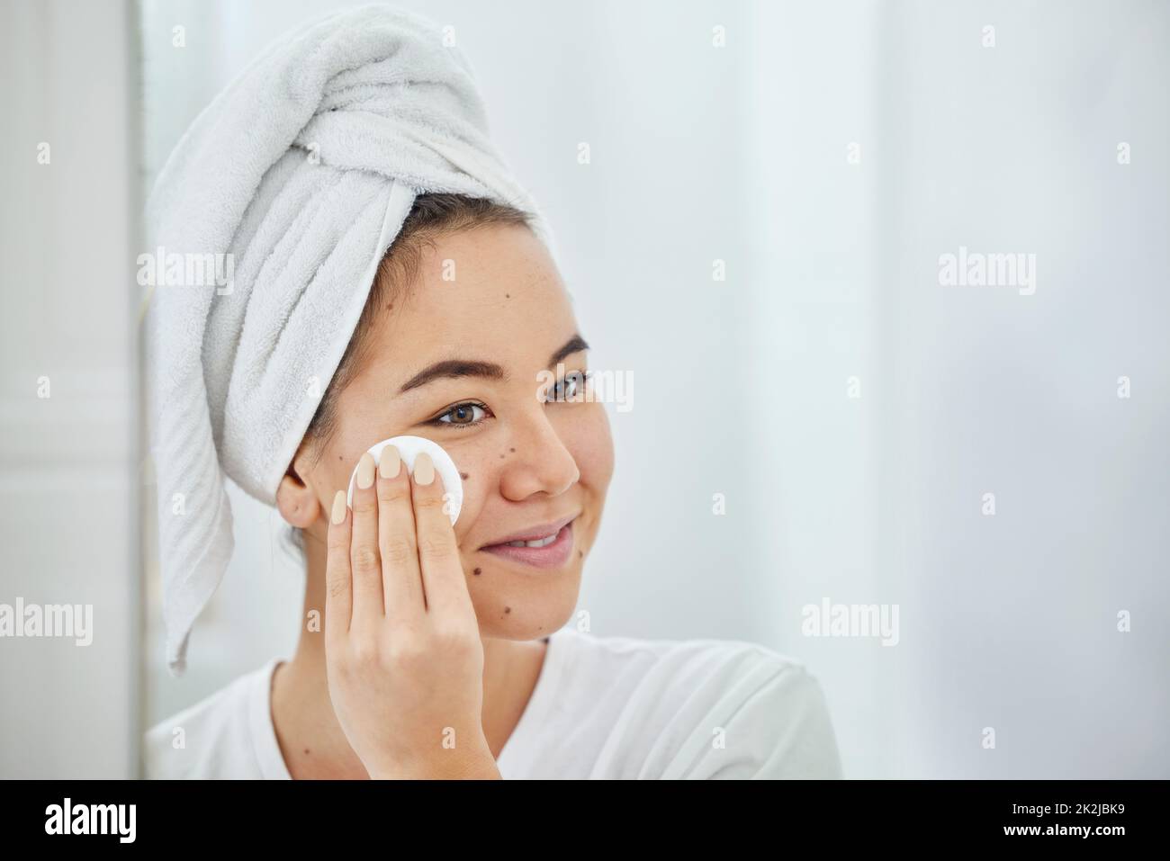 Prendermi cura di me mi fa felice. Scatto di una giovane donna che pulisce il viso con un batuffolo di cotone in un bagno a casa. Foto Stock