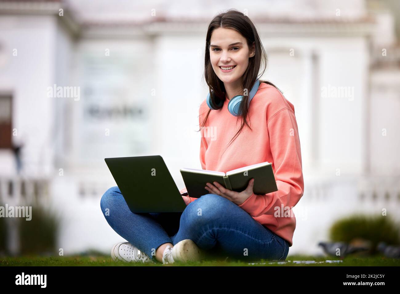 Im studiando per il mio ultimo esame. Scatto di una studentessa femminile che usa il suo portatile e il suo notebook mentre si siede all'esterno. Foto Stock
