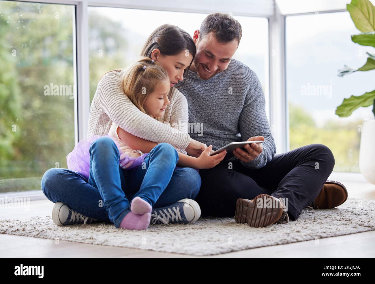 Felicità personificata. Scatto di una giovane famiglia con un tablet digitale a casa. Foto Stock