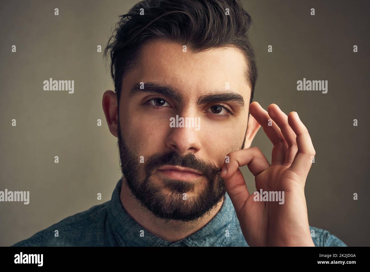 Perché un uomo dovrebbe assomiglia ad un uomo. Scatto corto di un giovane che gli attorciglia i baffi. Foto Stock
