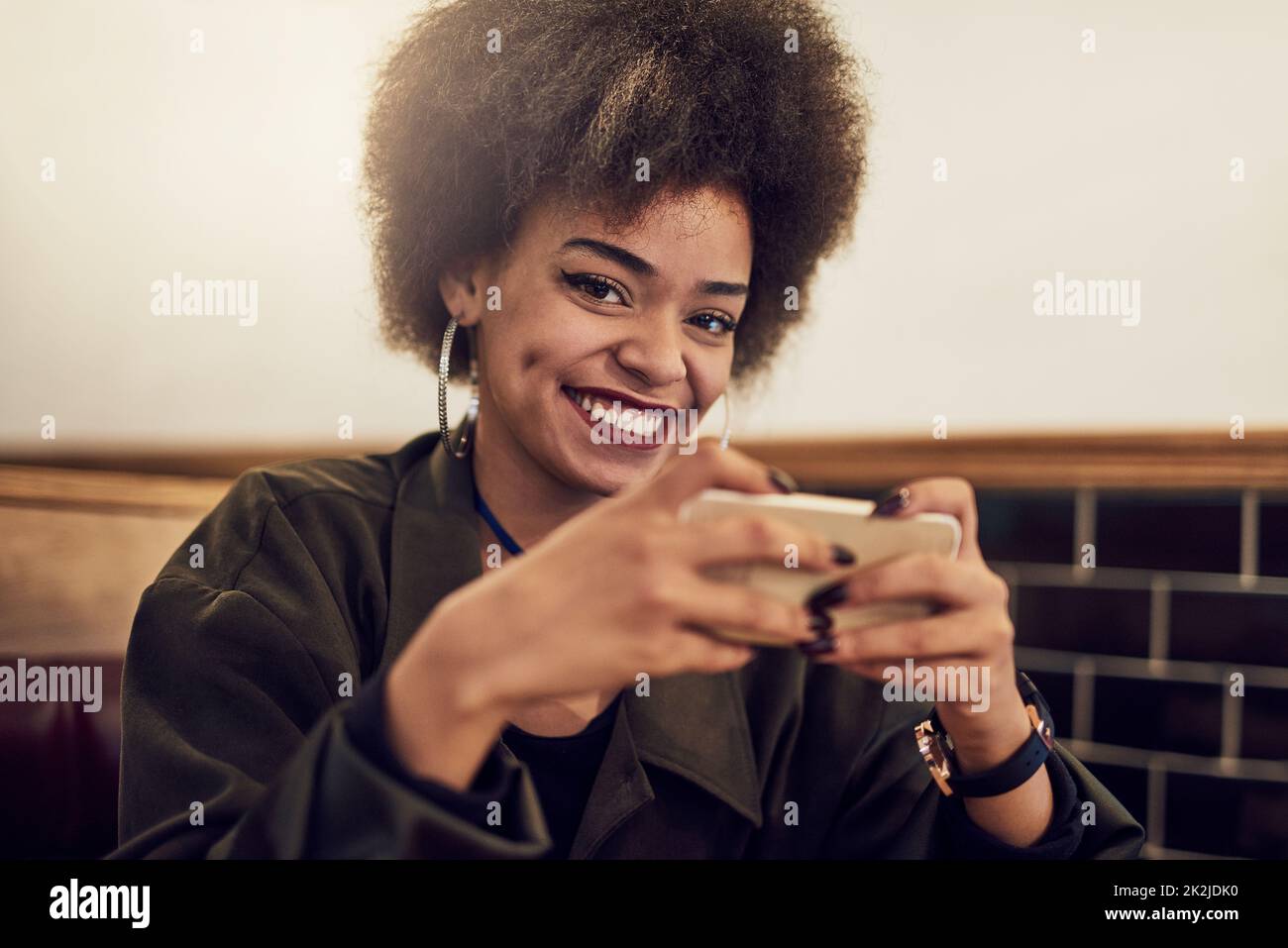 Sfruttare al massimo il mio tempo libero. Ritratto di una bella giovane donna utilizzando il suo cellulare in un caffè. Foto Stock