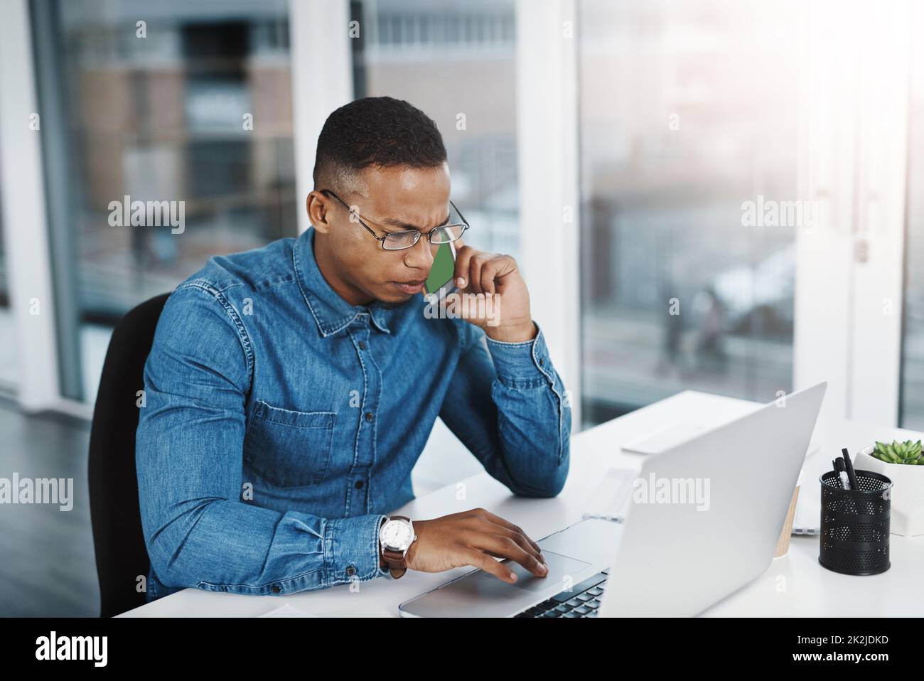 Queste cifre sono abbastanza sommate. Scatto di un giovane uomo d'affari con uno sguardo serio sul suo volto prendendo una telefonata in ufficio. Foto Stock