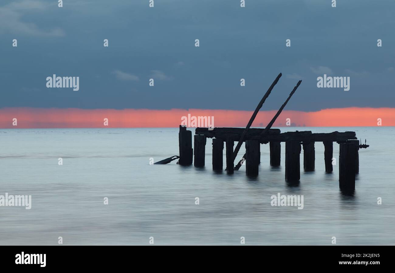 Lunga esposizione del vecchio molo di legno a Snettisham al tramonto con l'avvicinarsi della nuvola piovosa, Snettisham UK Foto Stock