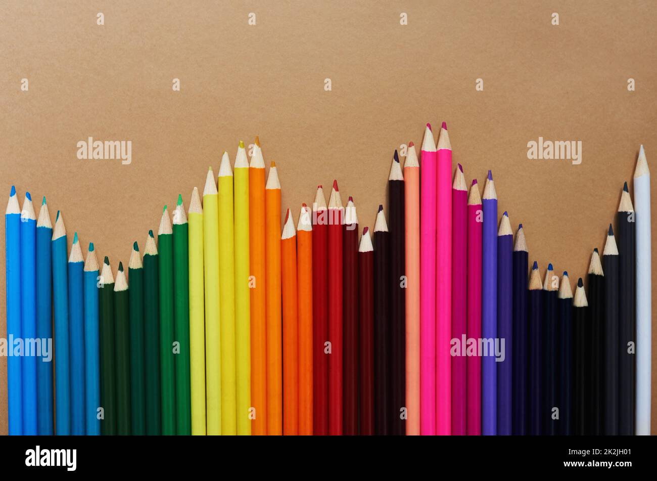 Sia il motivo che la vita di someones è piena di colore. Studio girato di matite di colori diversi su uno sfondo marrone. Foto Stock