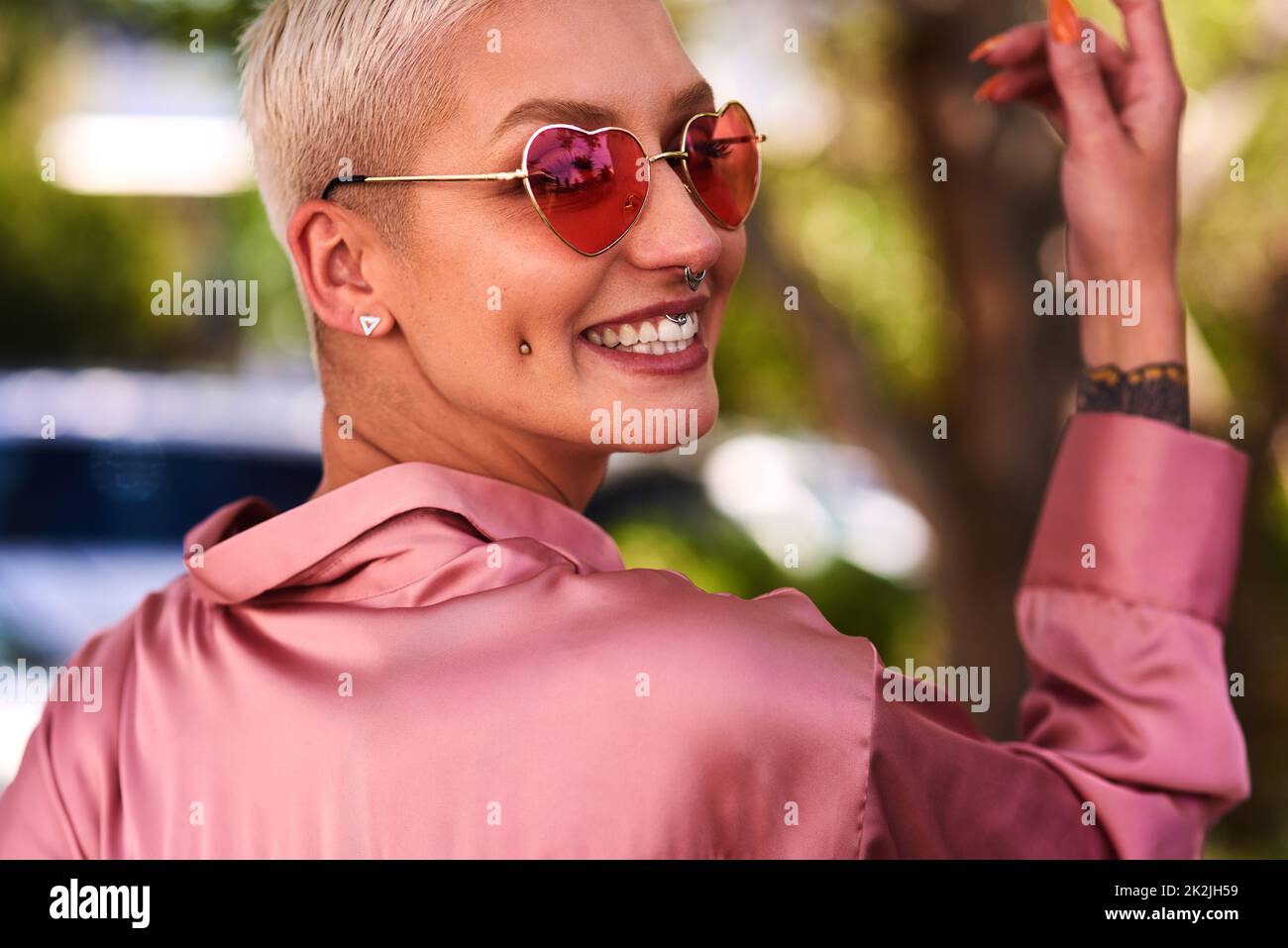La felicità sembra buona su chiunque. Primo piano ritratto di una giovane donna attraente ed elegante che indossa occhiali da sole rilassante in un parco all'aperto. Foto Stock