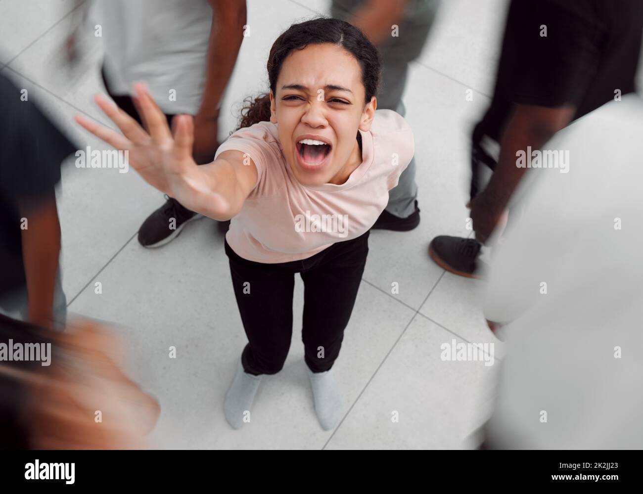 Sentitemi urlare in agonia. Scatto di una giovane donna che sperimenta malattie mentali mentre è circondata da persone all'interno. Foto Stock