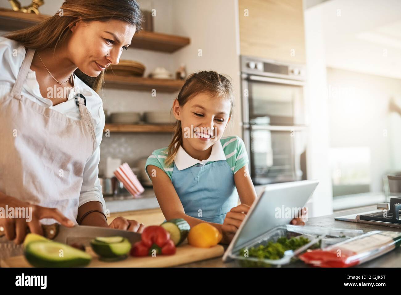 Amano provare cose nuove. Shot di una madre e di sua figlia giovane che provano insieme una nuova ricetta in cucina. Foto Stock