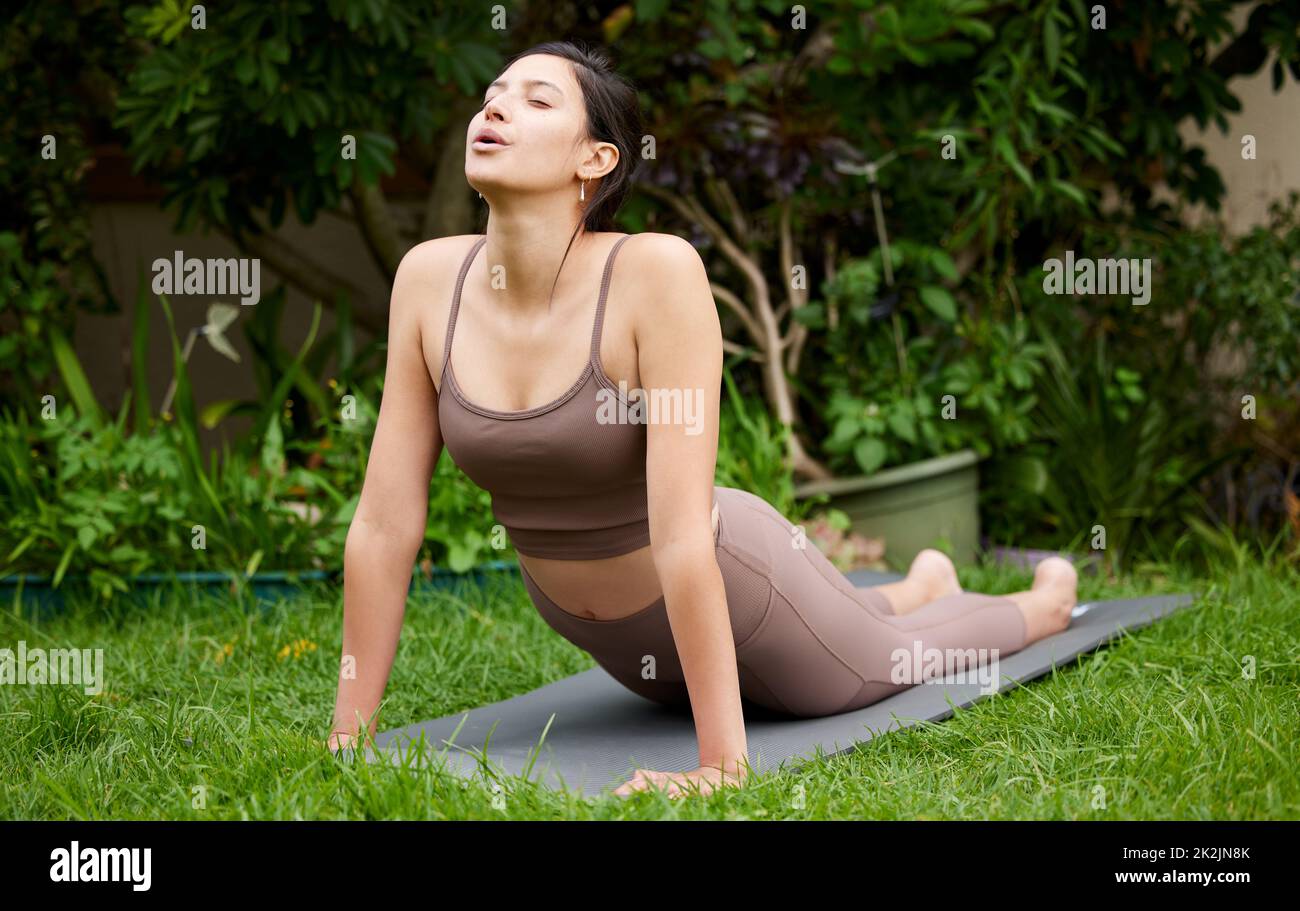 Lo yoga vi permetterà di scoprire il vostro luogo di pace. Scatto di una giovane donna che fa un tratto di cobra mentre si esercita all'aperto. Foto Stock