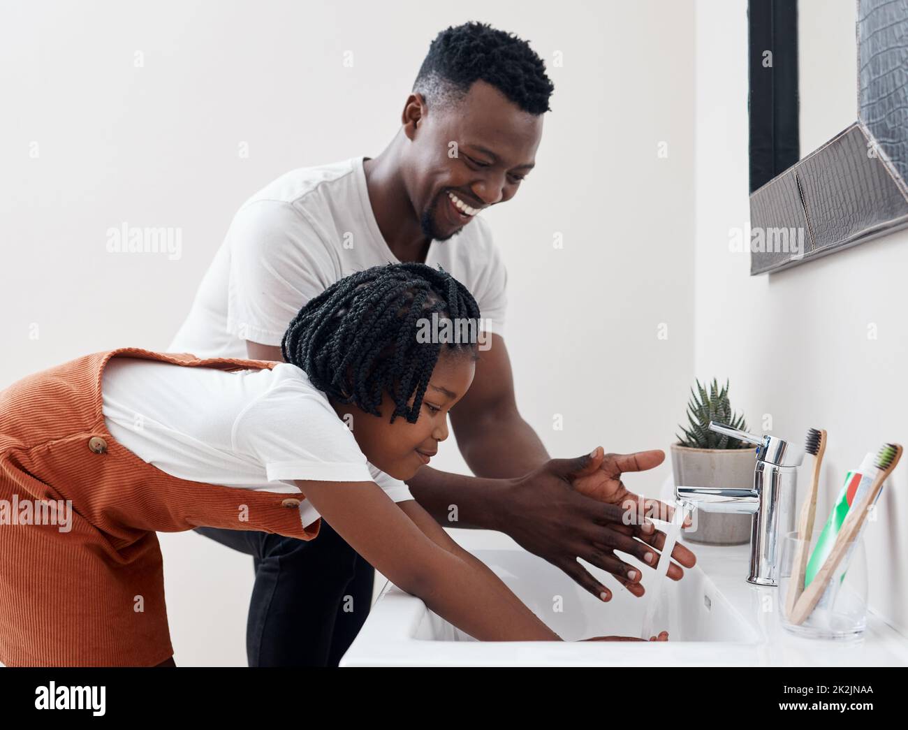 Tempo di lavare tutti quei germi fuori. Colpo di un giovane padre che aiuta sua figlia a lavarsi le mani nel bagno di casa. Foto Stock