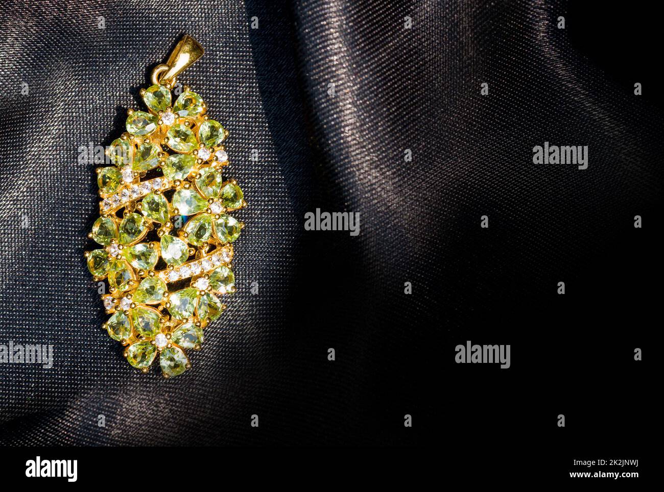 Peridot e diamante Jewel o gemme pendente su sfondo nero lucido tessuto poliestere. Collezione di accessori per gemme naturali. Foto studio Foto Stock