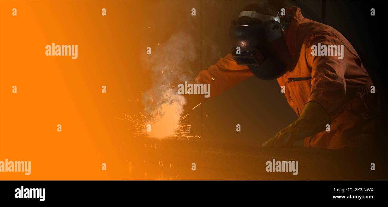 Il lavoratore dell'industria del metallo sta saldando la lamiera d'acciaio per i progetti immobiliari ricevuti. Sparkler su sfondo nero, primo piano. Lavori pesanti in fabbrica. Foto Stock