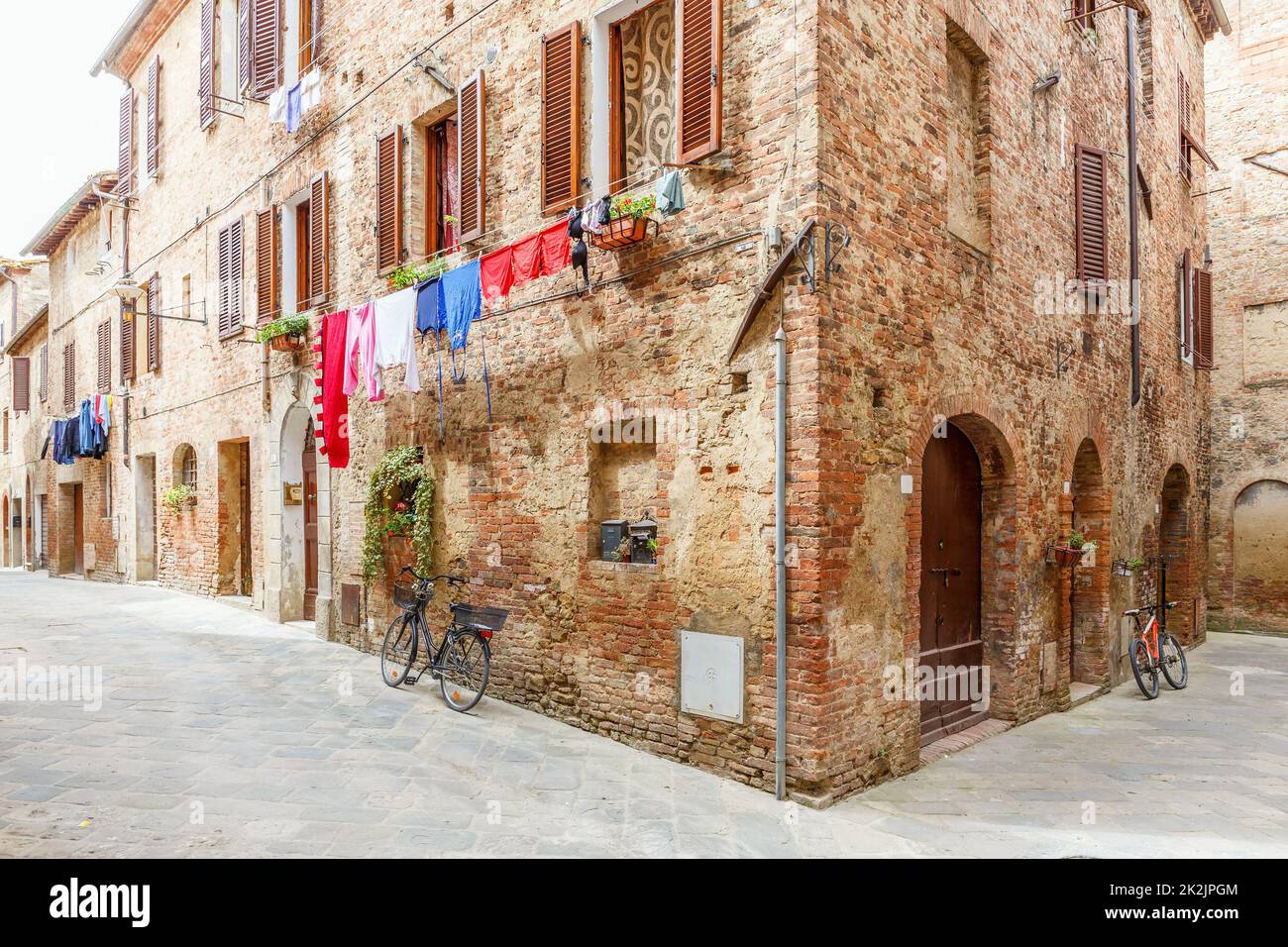 Vicolo italiano con i panni appesi e le biciclette parcheggiate Foto Stock