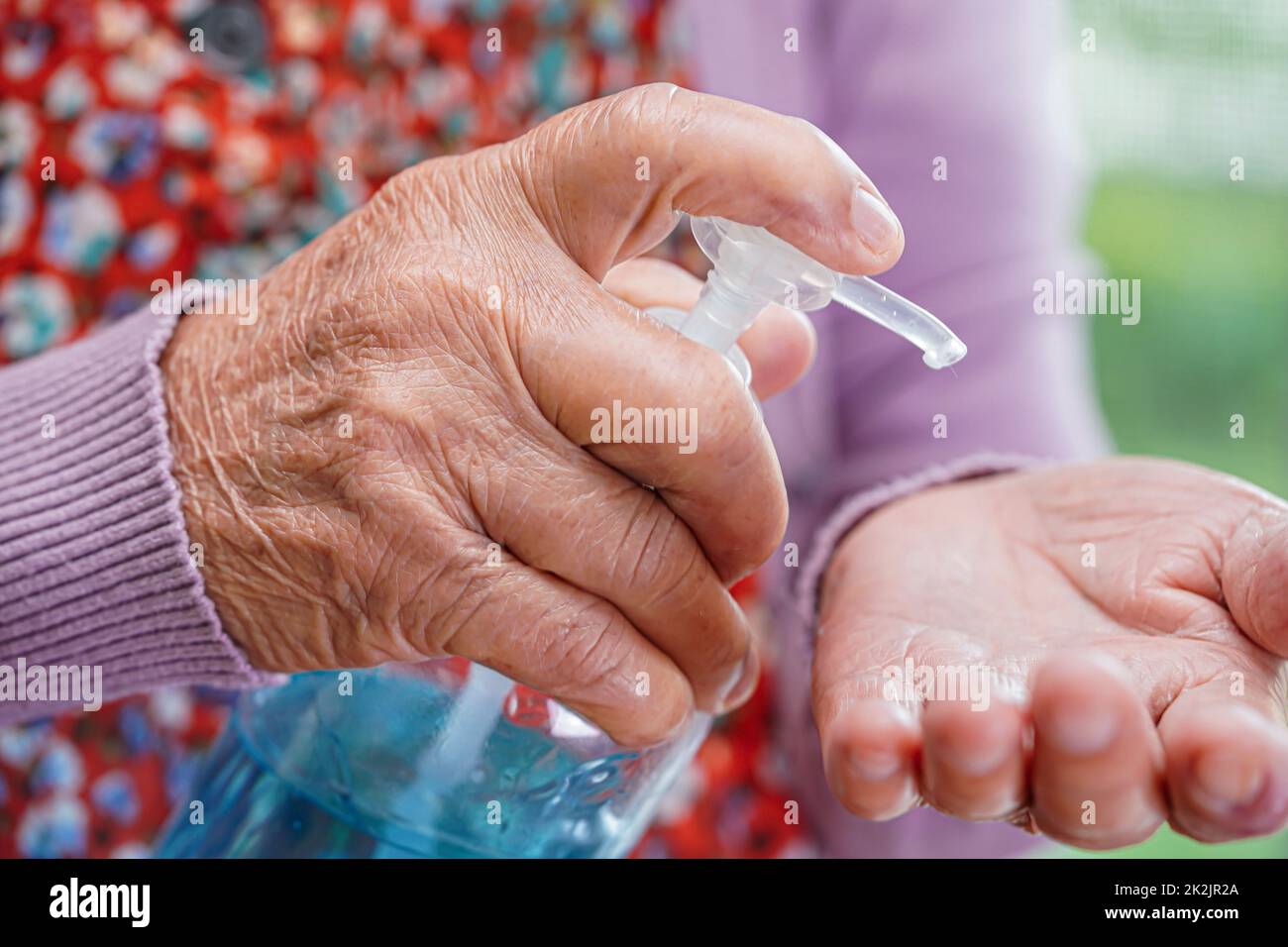 Asiatico donna anziana premere blu alcol sanitizer gel per il lavaggio mani proteggere infezione coronavirus. Foto Stock