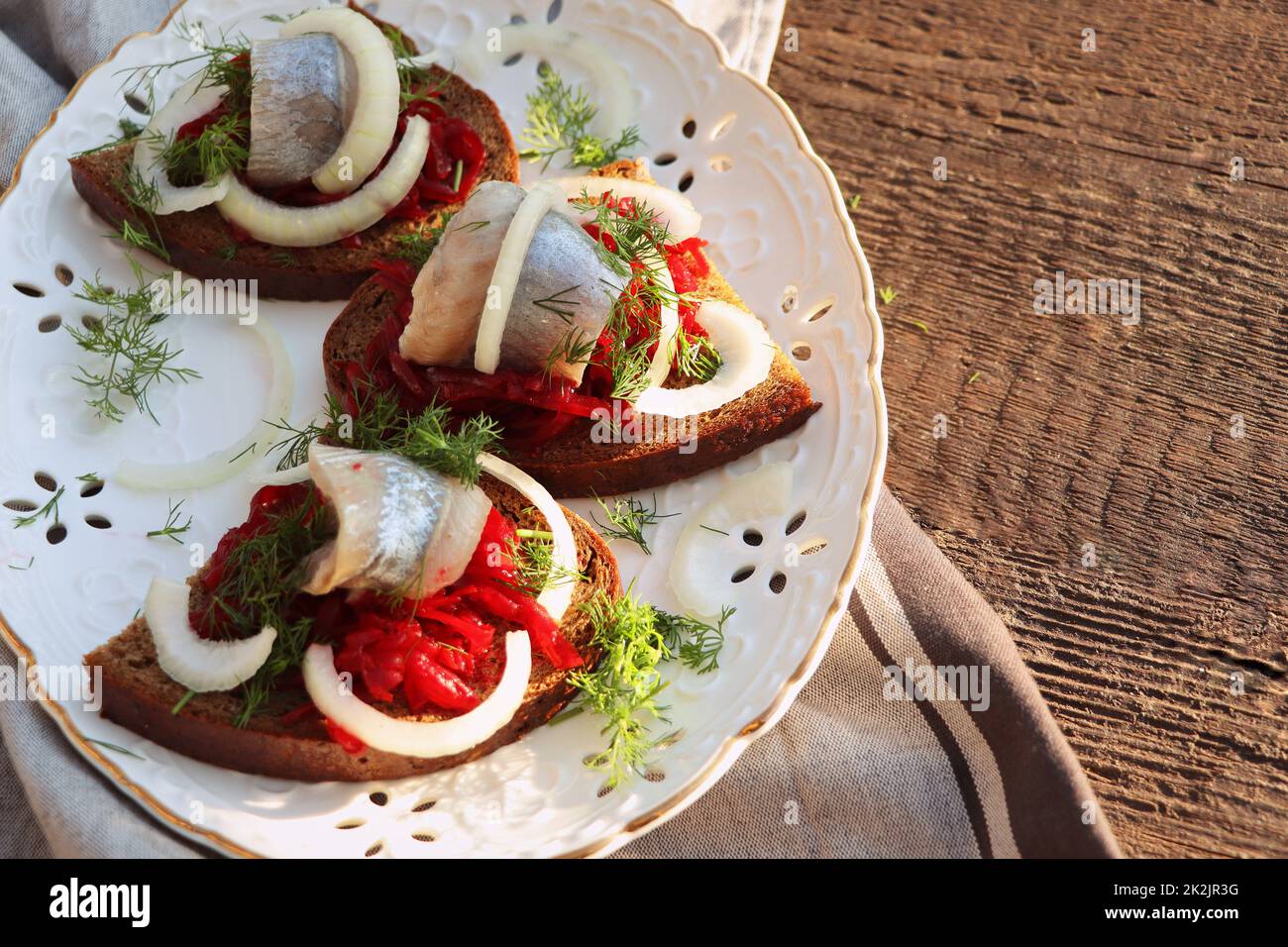 Filetto di aringa. Cucina scandinava. Sandwich con fette di filetto di aringa atlantica sottaceto, insalata di barbabietole, cipolla e microgreen. Foto Stock