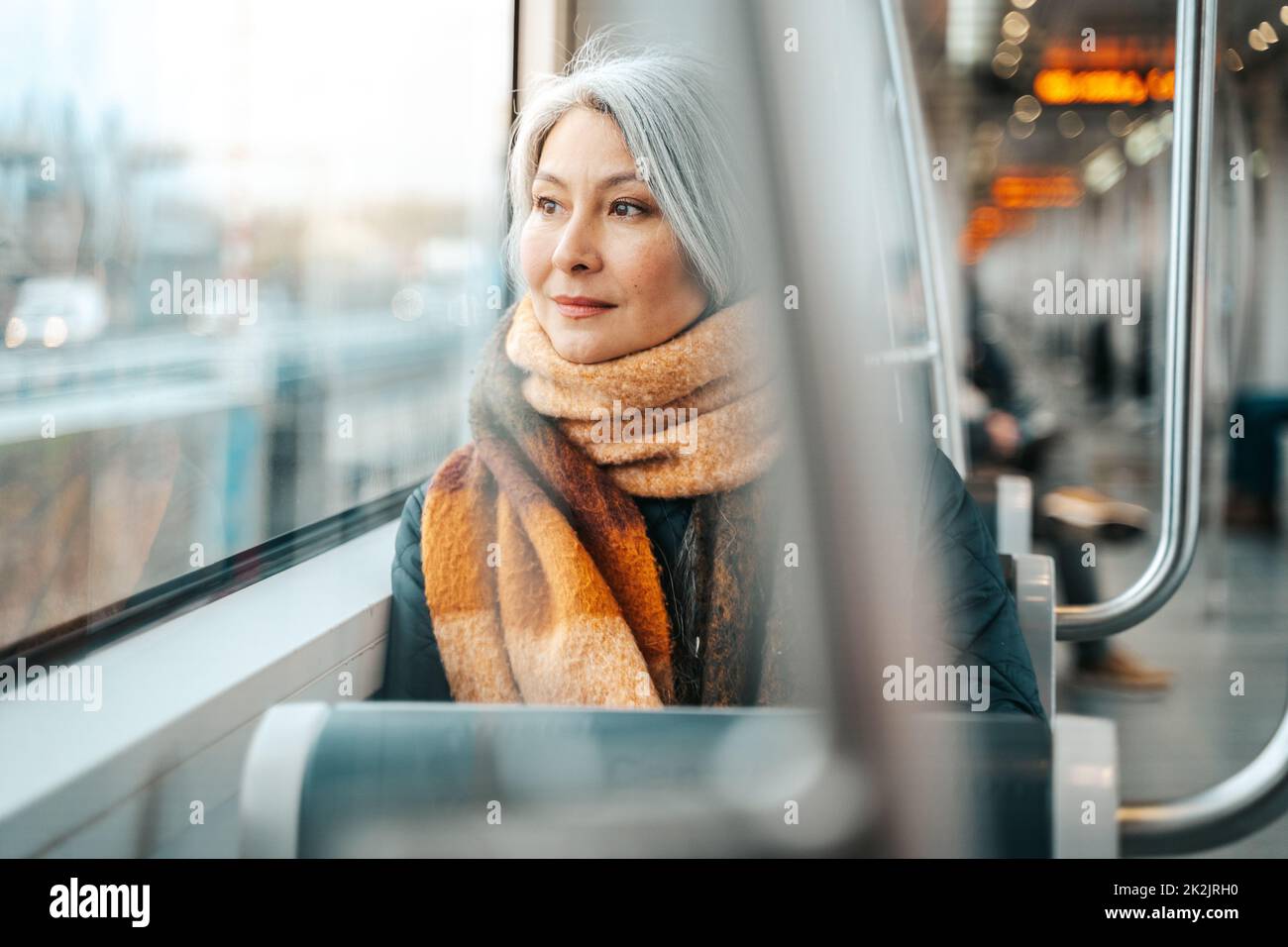 La donna anziana seduta su un treno è in viaggio verso la destinazione Foto Stock