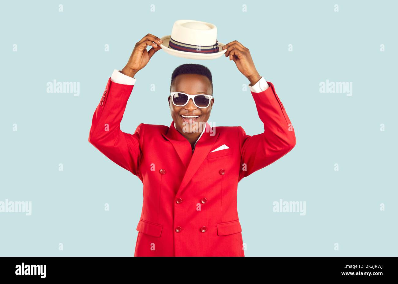 Buon Signore afro-americano in vestito rosso funky toglie il suo cappello e dice Ciao Foto Stock