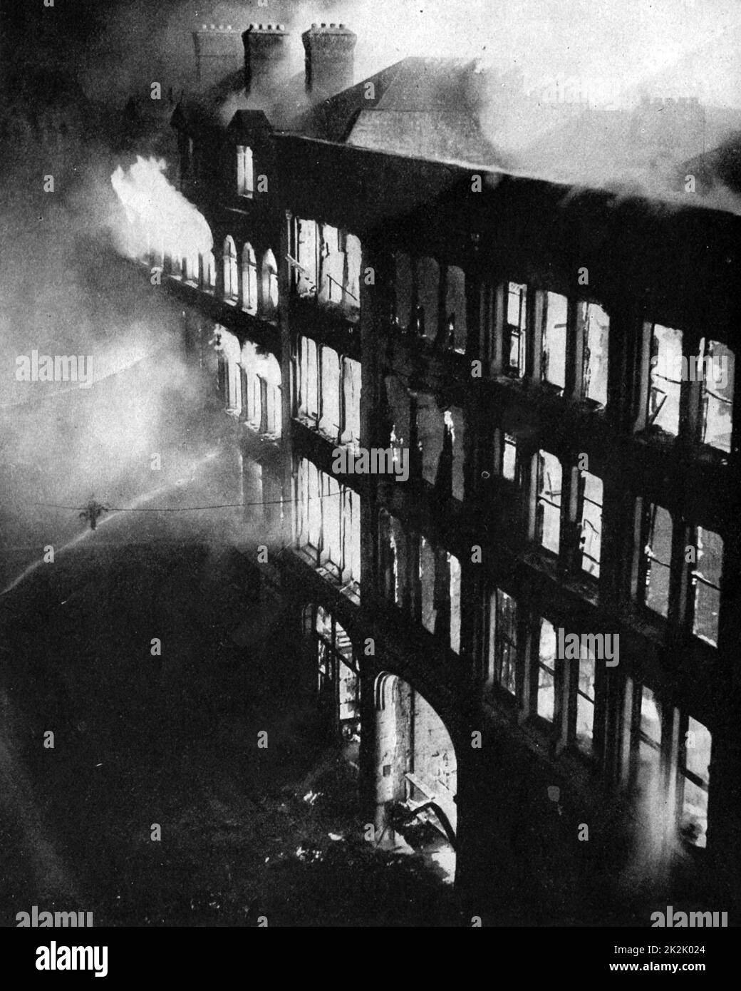 Magazzini nella parte orientale di Londra bruciati, messo in luce dalle bombe caduto da Lufwaffle (forze aeree tedesche) aerei durante il Blitz la notte del 24-25 agosto 1940. Vigili del fuoco londinesi che tentano di spegnere le fiamme con manichette. Danni. Foto Stock