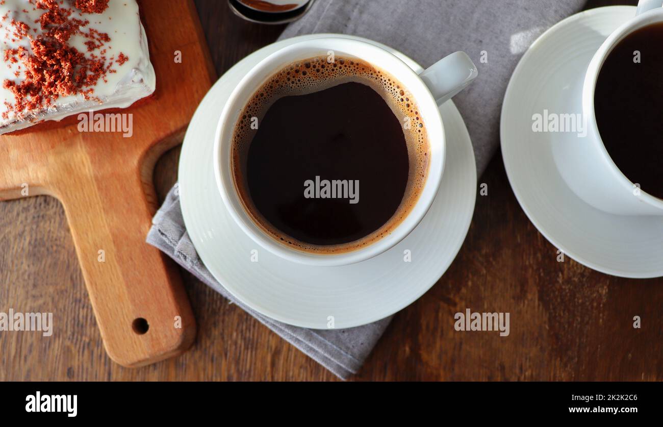 Torta di velluto rosso e due tazze di caffè per colazione su sfondo di legno. Dessert gustoso. Primo piano Foto Stock