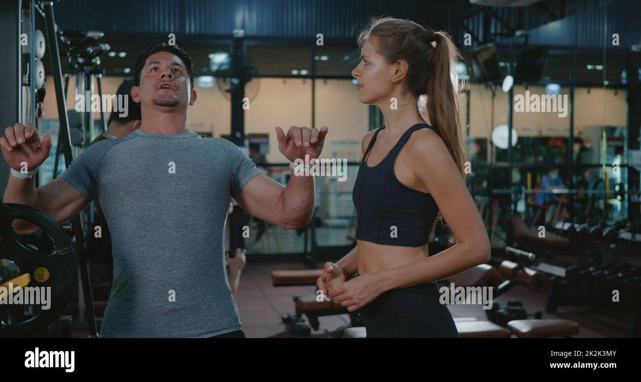 Allenatore di fitness che spiega l'allenamento banco di sollevamento pesi con il programma di barbell a una donna cliente Foto Stock