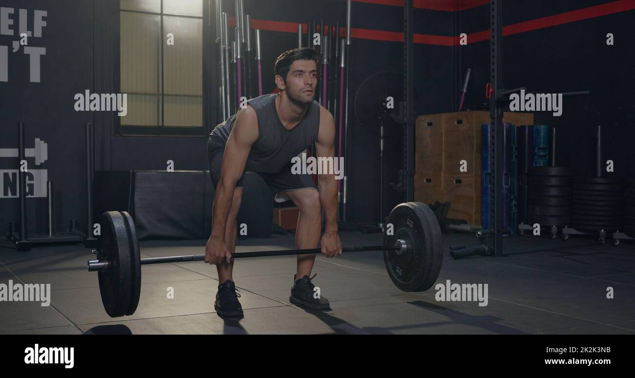 Muscoloso giovane uomo caucasico esercizi di allenamento con sollevamento pesi pesante Barbell Foto Stock