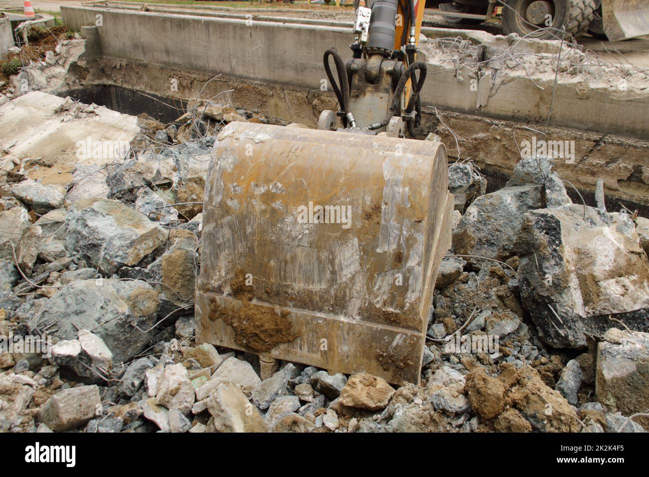 Caricamento di macerie da costruzione con un escavatore in un ambiente polveroso Foto Stock