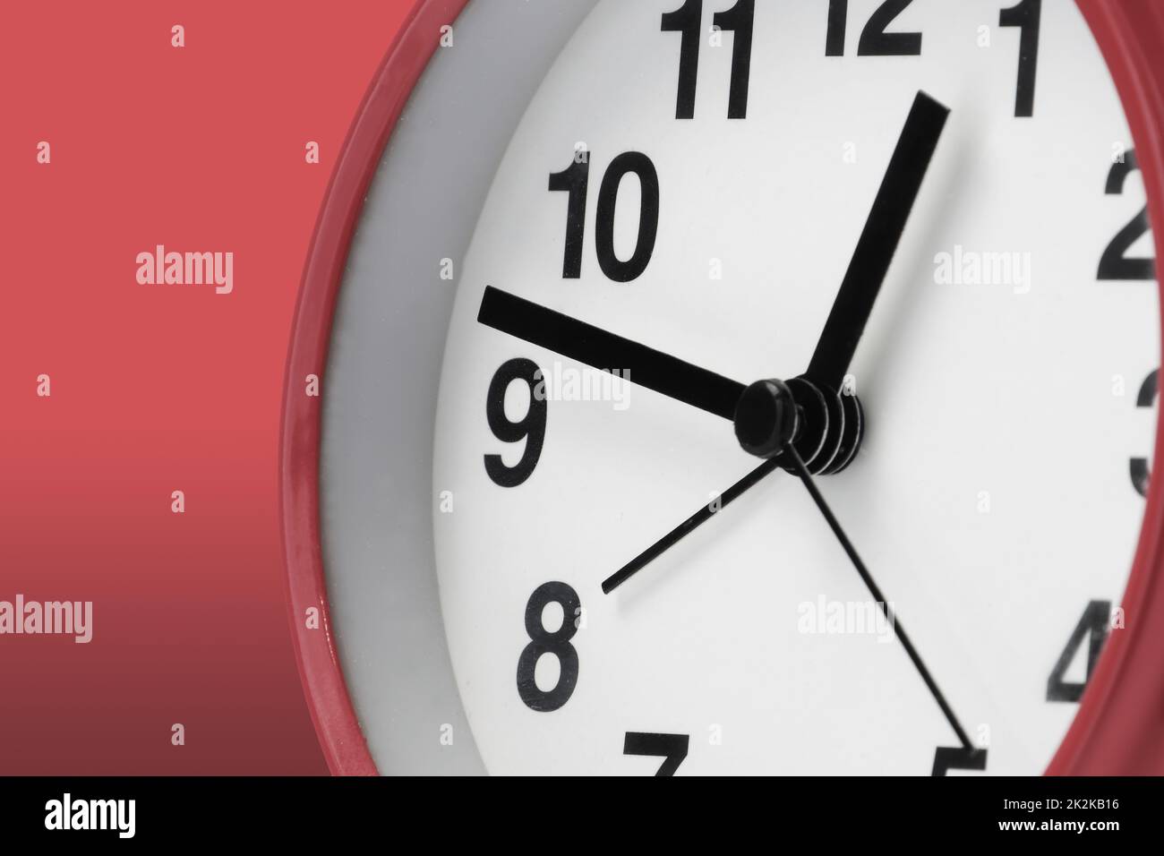 Orologio faccia bianca con le mani nere su sfondo rosso Foto Stock
