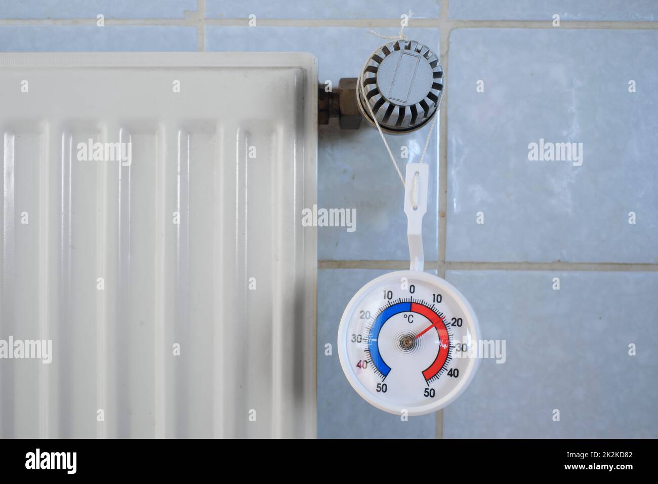 Radiatore, valvola e termometro che mostrano bassa temperatura, carenza di gas e petrolio da riscaldamento a causa dell'embargo del petrolio e del gas russi in europa Foto Stock