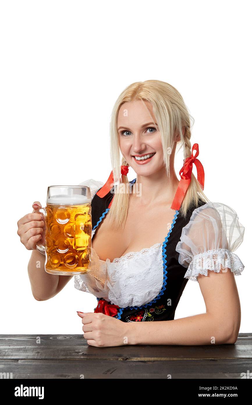 Giovane donna bavarese a dirndl seduta al tavolo con birra su sfondo bianco Foto Stock