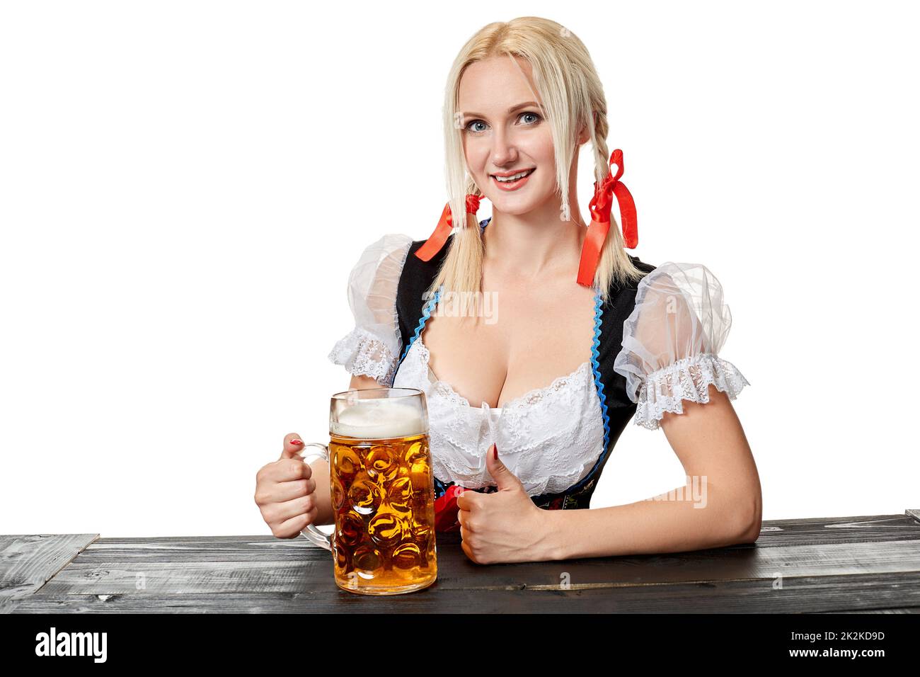 Giovane donna bavarese a dirndl seduta al tavolo con birra su sfondo bianco Foto Stock