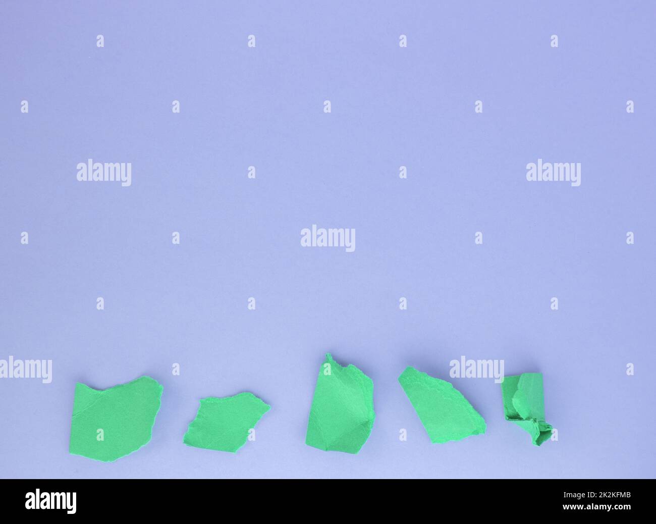 Un mazzo di palle di carta verde sgualcita su sfondo viola sul bordo inferiore. Il concetto di minimalismo, una copia dello spazio Foto Stock