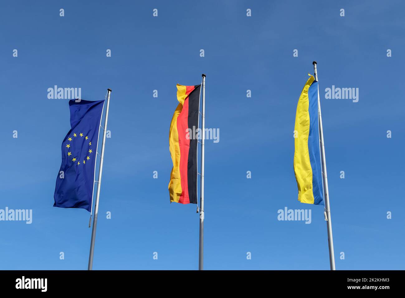 Le bandiere di Ucraina, Germania e Unione europea volano fianco a fianco contro il cielo blu. Foto Stock